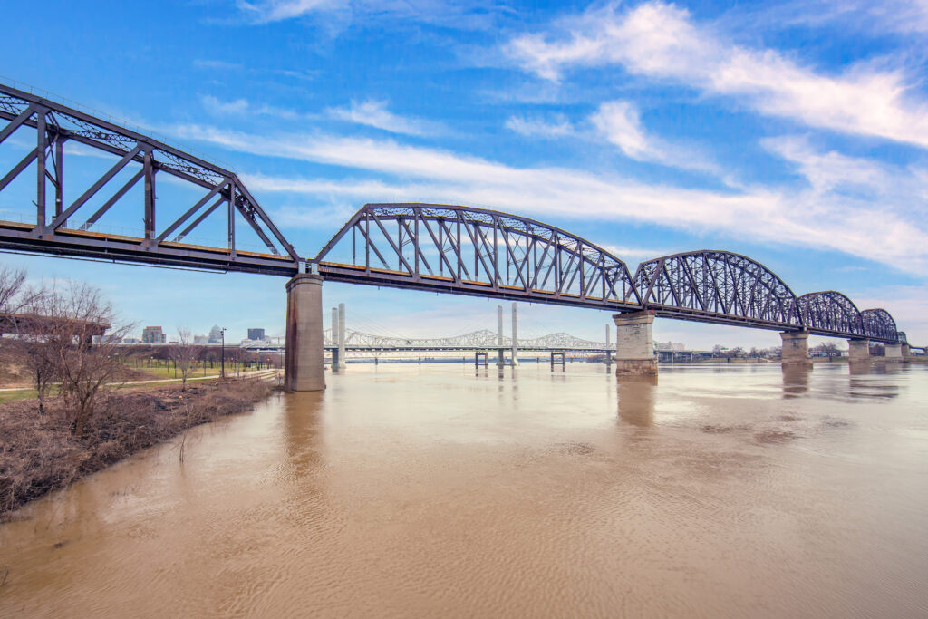 A view of a bridge crossing a muddy river with another bridge in the background
