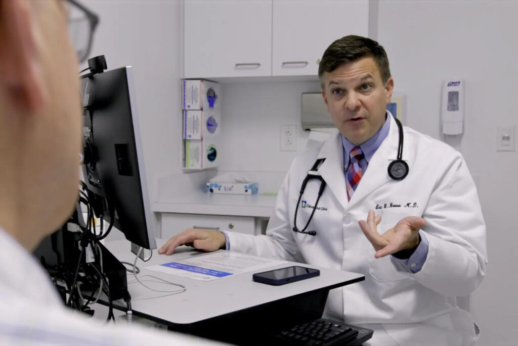 Can I Opt Out of Having My Doctor Take Notes With AI? A male doctor in a white coak speaks to someone out of frame.